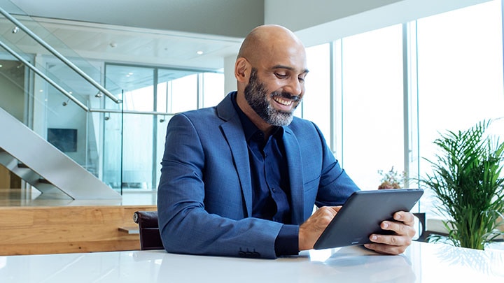 Smiling man looking at finances on smart tablet