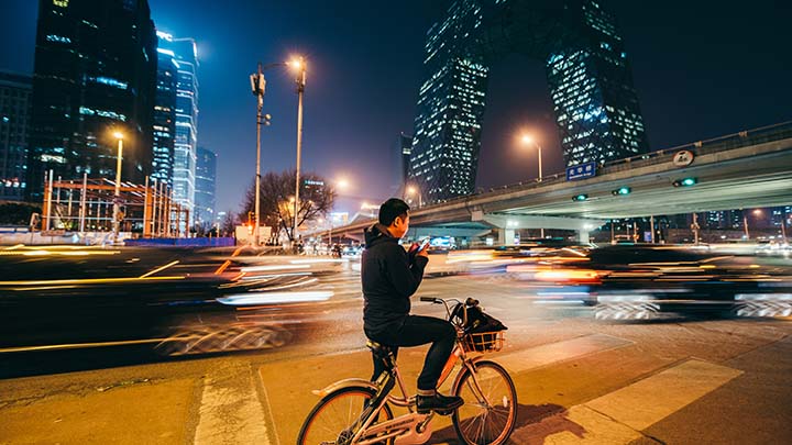 Man looking at mobile phone on a bike at night