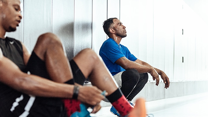 Male atheletes taking a break on locker room floor