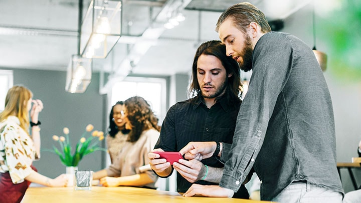 Two male colleagues controlling lighting with smart phone