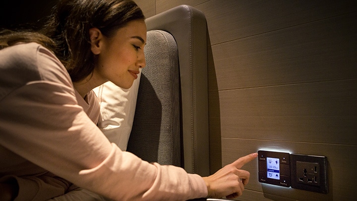 Mujer usando el panel de control de las habitaciones de un hotel