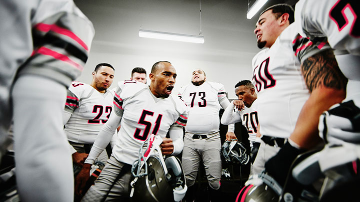 Football player leading team motivational chant in changing room