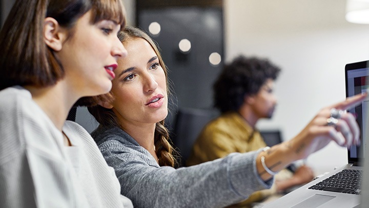 Two female colleagues discussing work on computer