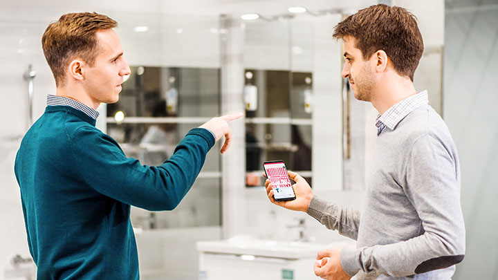 Two men discussing product location in store with smart phone navigation