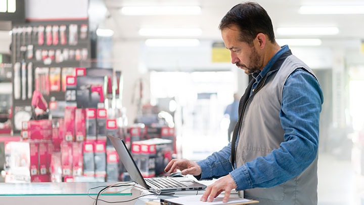 Bedrijfseigenaar in een hardwarewinkel die op zijn laptop werkt