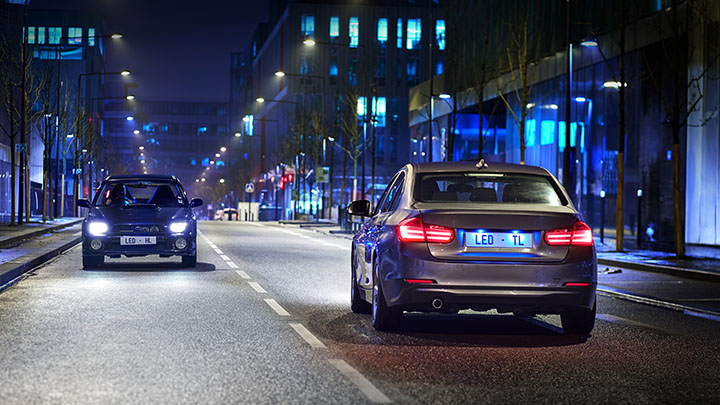 Street level view of two cars on the road at night