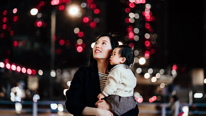 Mother and  baby looking up while walking in city at night