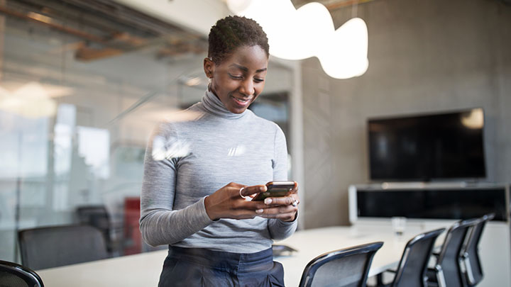 Vrouw die naar een telefoon kijkt in een vergaderruimte