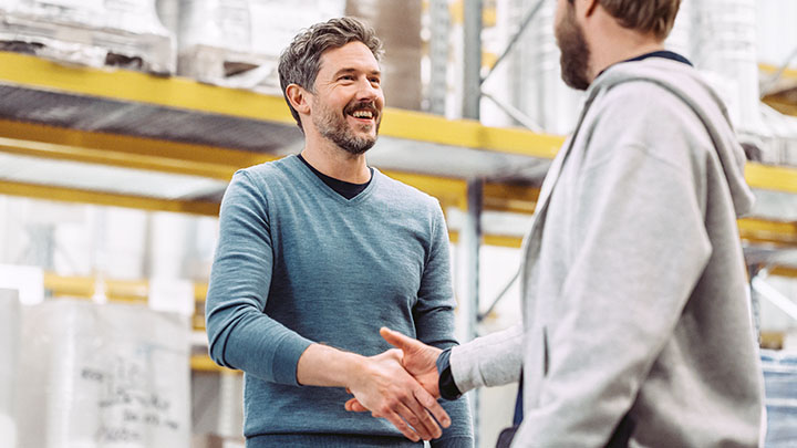 Two production managers shaking hands in warehouse