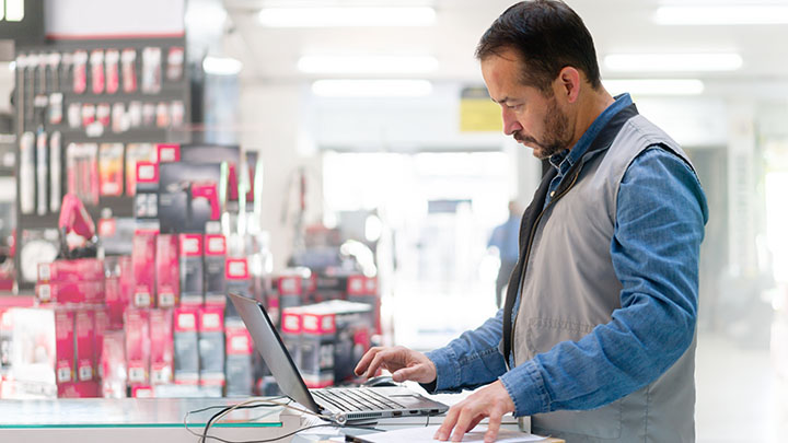 Bedrijfseigenaar in een hardwarewinkel die op zijn laptop werkt