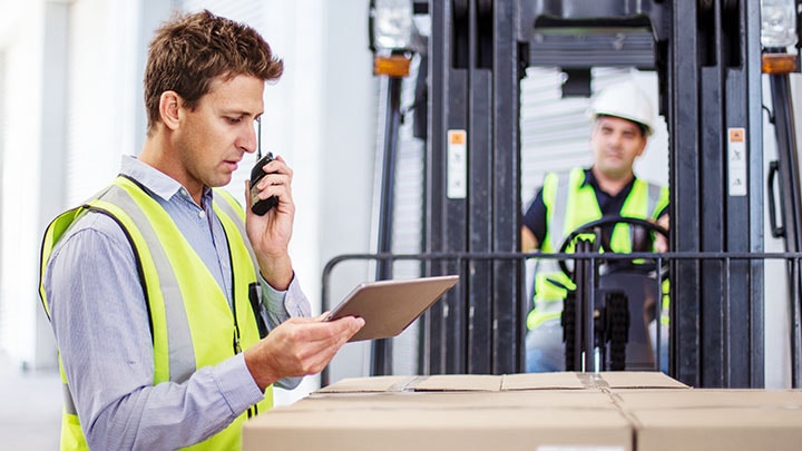 Workers at a large warehouse on tablet and walkie talkie