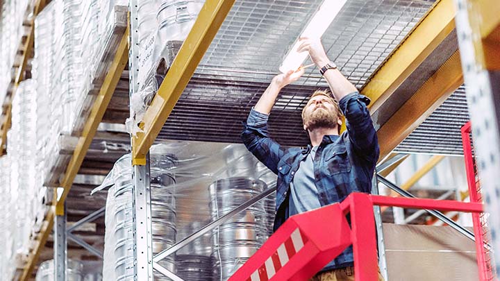 Maintence man replacing light in warehouse