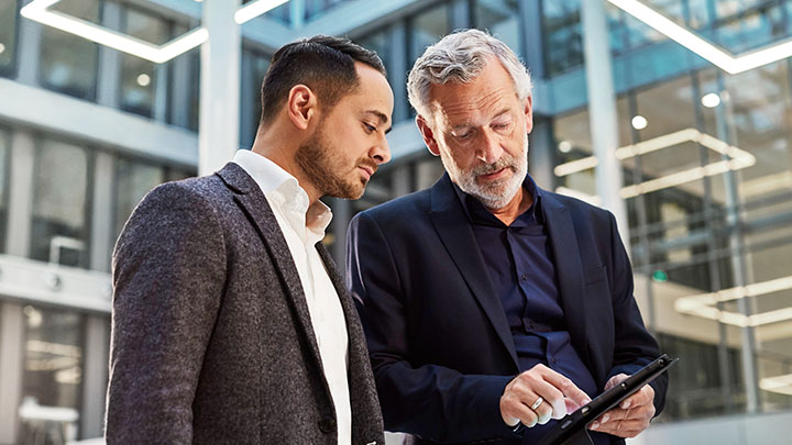 Two office workers discussing lighting on tablet