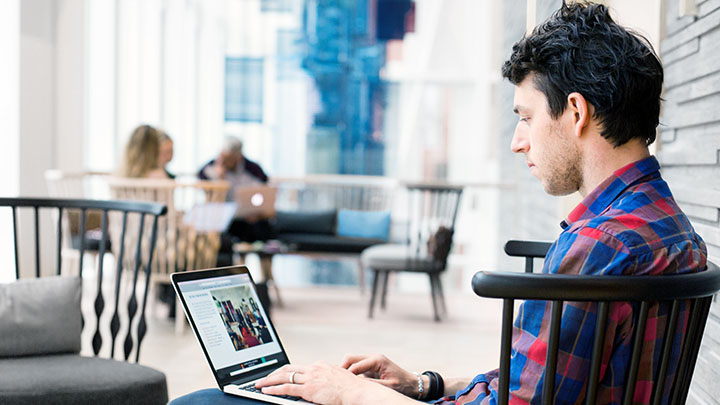 Zijaanzicht van een zakenman die een laptop gebruikt in een lobby