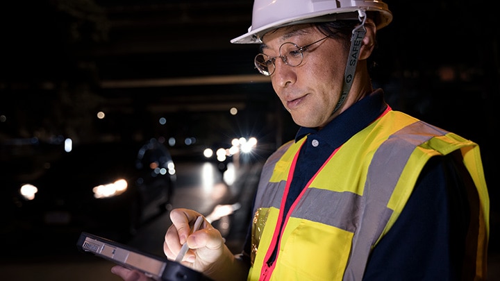 Highway operator using a tablet  to look at data on roadside at night