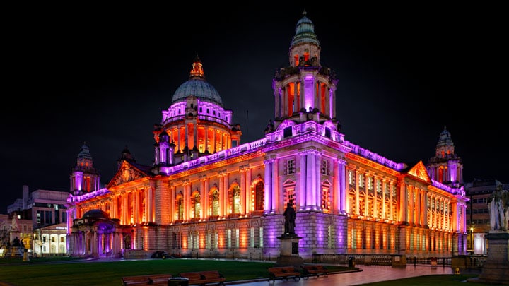 Stadhuis van Belfast in de avond, verlicht met paarse en oranje verlichting