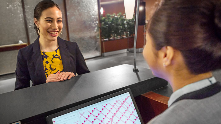 Two colleagues talking over a reception counter in a hotel lobby