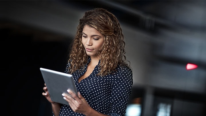 A woman in a dark room looking at a tablet