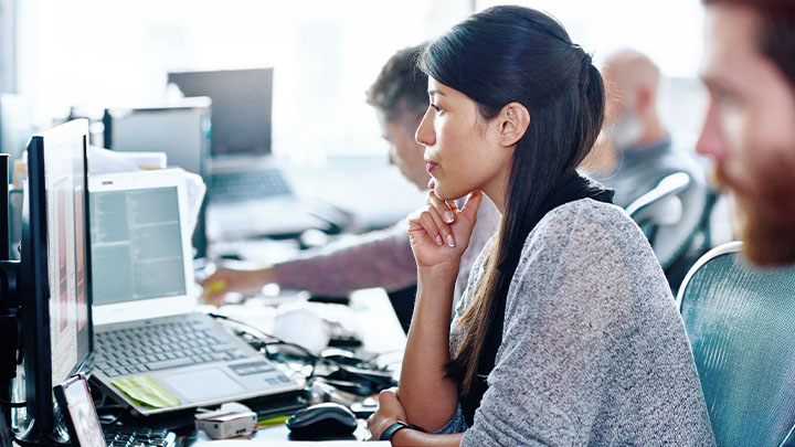 A worker in a busy office looking at their laptop screen