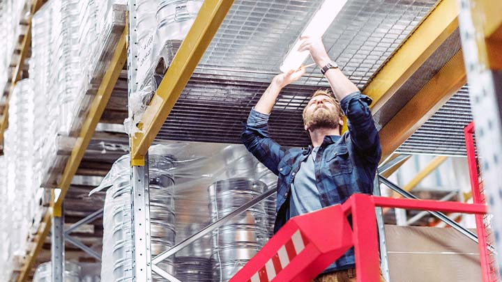 A worker in a warehouse replacing a strip-light