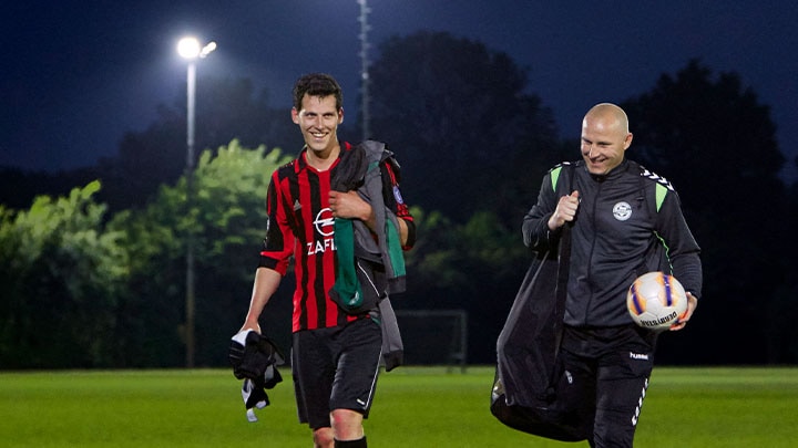 Un joueur de football et son entraîneur sortant du terrain en souriant