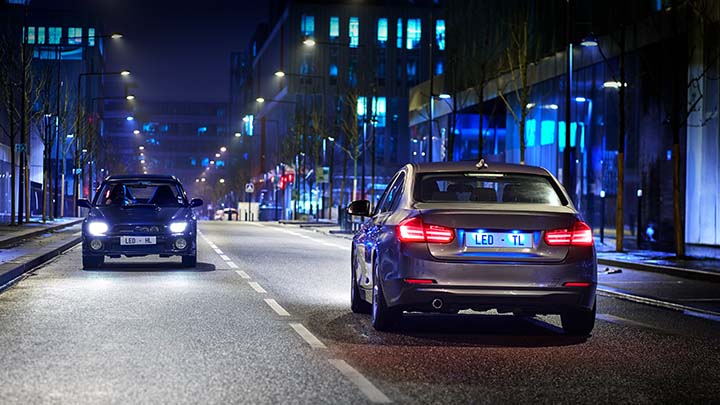 Zwei Autos fahren nachts in einer Stadt aneinander vorbei