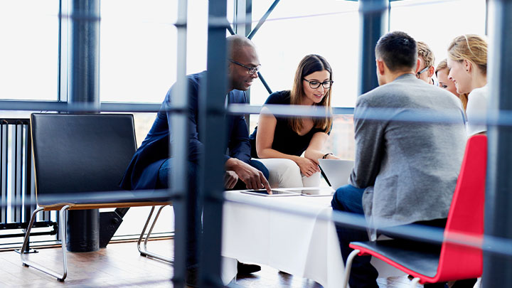 A group of colleagues sitting down in a casual meeting area dicussing insights and data