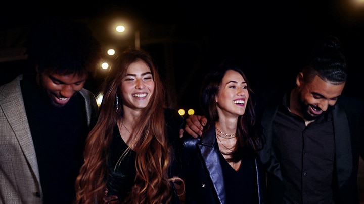 Two couples walking along a city street at night