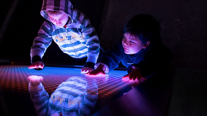 Zwei Kinder spielen an einer LED-Installation