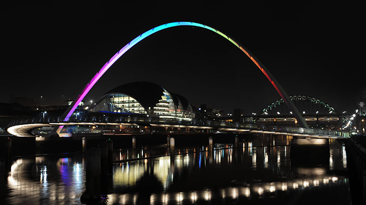 Gateshead Millennium Bridge iluminado con los colores del arcoíris de noche 