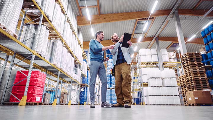 Two workers walking through a warehouse with a clipboard
