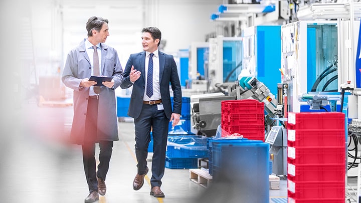 Engineer giving manager a guided tour through a factory