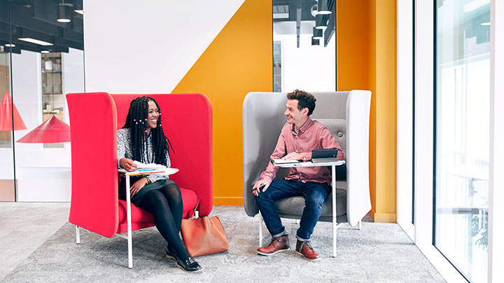 Two colleagues talking to each other in a brightly colored office space