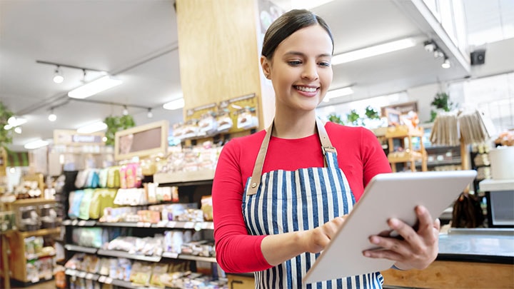 Een supermarktmedewerker in een schort die de winkelverlichting regelt op een tablet