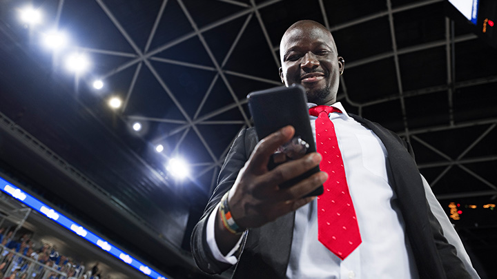 Un manager de football contrôlant l'éclairage d'un stade sur son smartphone