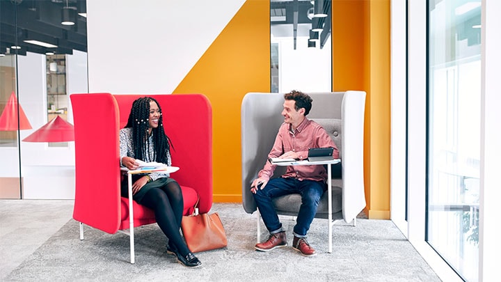 Two employees sat in office chairs talking