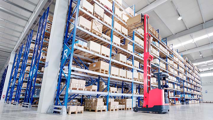 Forklift carrying cardboard box in warehouse