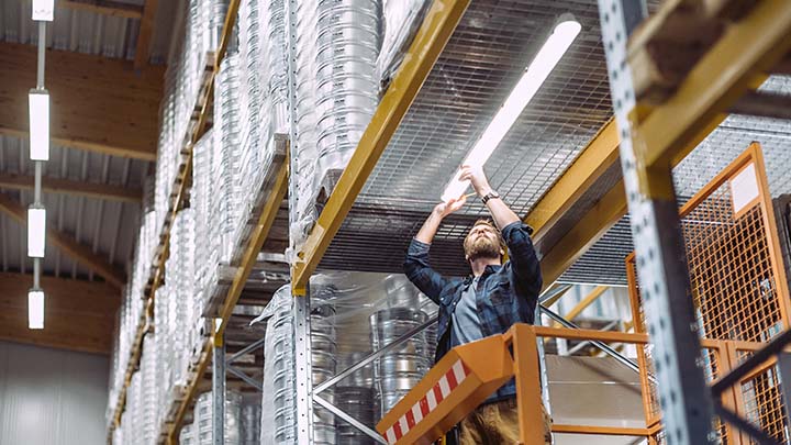 Man installing luminaire in warehouse