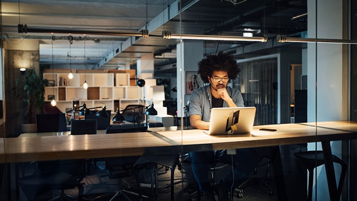 Un empresario trabajando en la computadora portátil mientras está sentado en el escritorio de la oficina