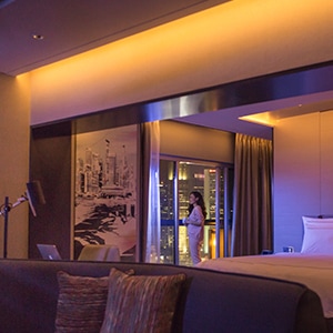 Woman standing at window in dimly-lit hotel room