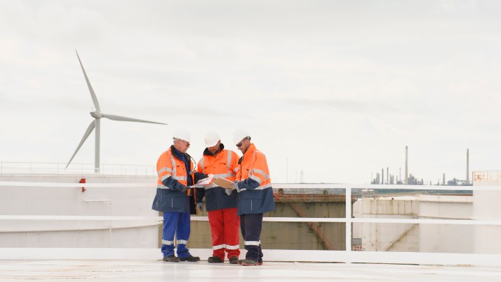 Equipo de operaciones de fábrica en el exterior con turbina eólica de fondo